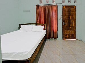 A room with a bed, a wooden door, and a radiator. - Hotel O Homestay Bang HajiNearLapangan Penujak ( Inen Gonggang) (Praya)