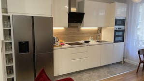 A modern kitchen with white cabinets, stainless steel appliances, a built-in oven, and a microwave.