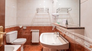 Casa de banho com sanita, lavatório e porta-toalhas.