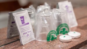 Uma bancada com diversos produtos para cabelo, incluindo embalagens de shampoo e condicionador, e algumas garrafas de shampoo vazias.
