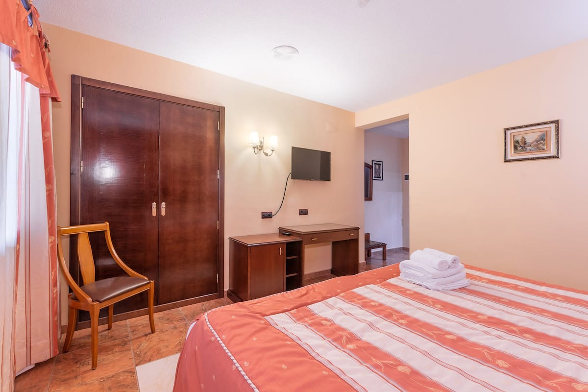 Une chambre d’hôtel comprenant un lit, un bureau, une chaise, une armoire et un téléviseur.
