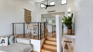 Un espacio habitable moderno con sofá, escalera y zona de cocina.