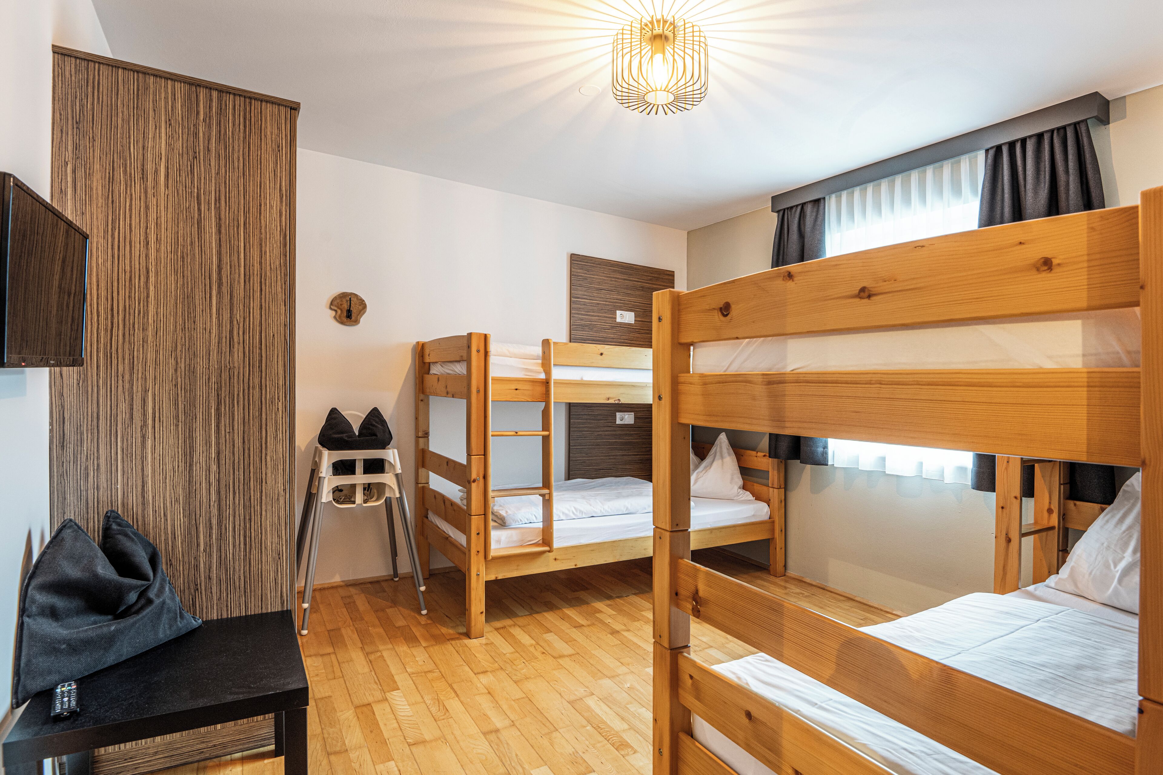 A room with bunk beds, a desk, and a chair.