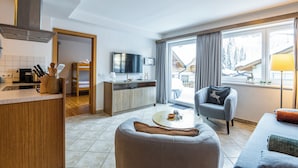 A modern kitchen with a dining area, a sofa, and a TV. - Haus Obauer (Wagrain)