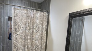 A bathroom with a shower curtain, toilet, vanity with a mirror, and a bathtub.