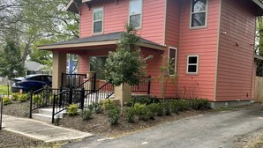 A two-story house with a red exterior, a front porch, and a small front yard.