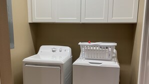A laundry area with two white washing machines and a white laundry basket.