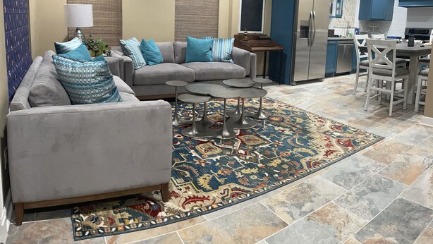 A modern living room with a grey sectional sofa, a coffee table, and a patterned rug.
