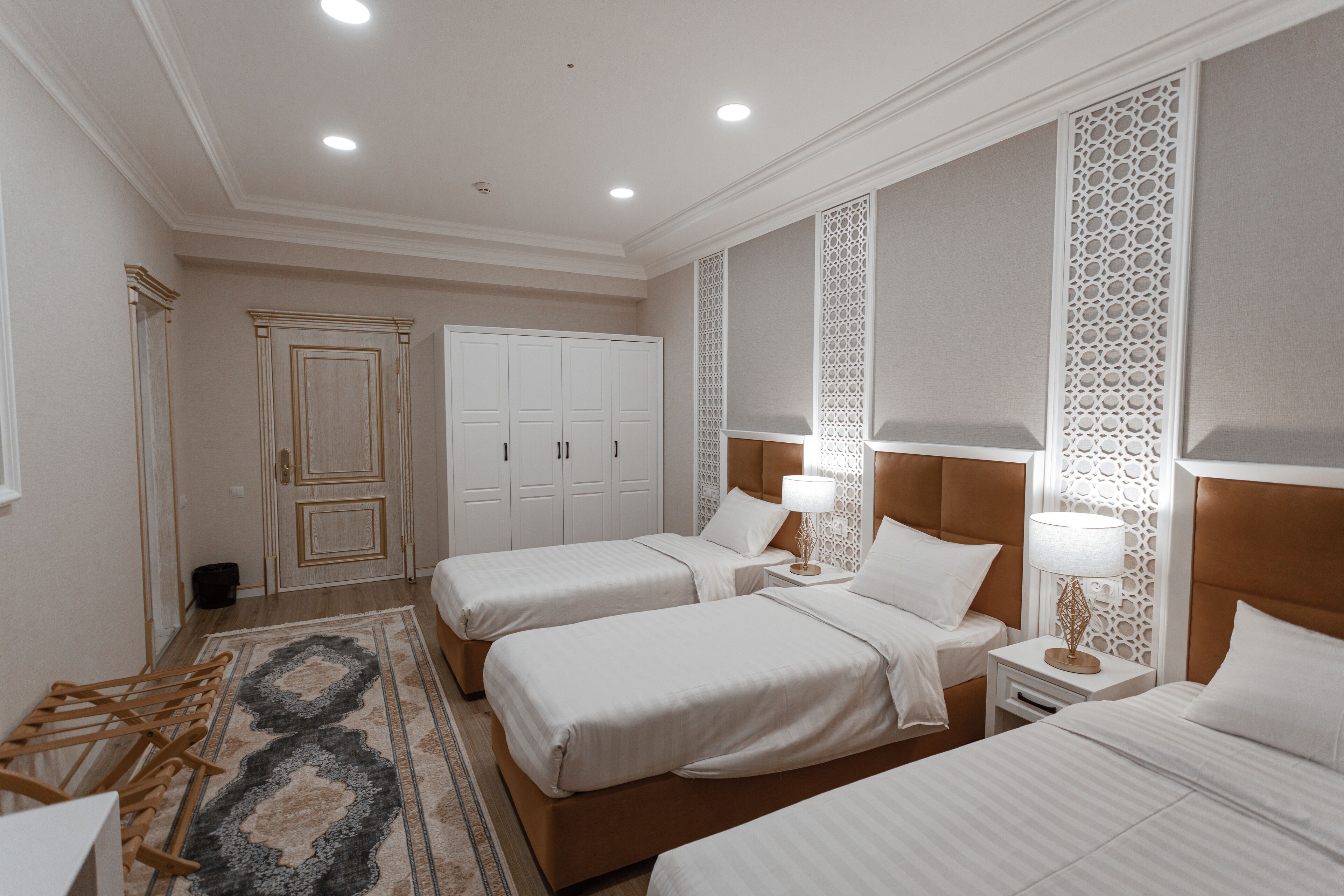 A hotel room with two beds, a large wardrobe, and a decorative wall panel.