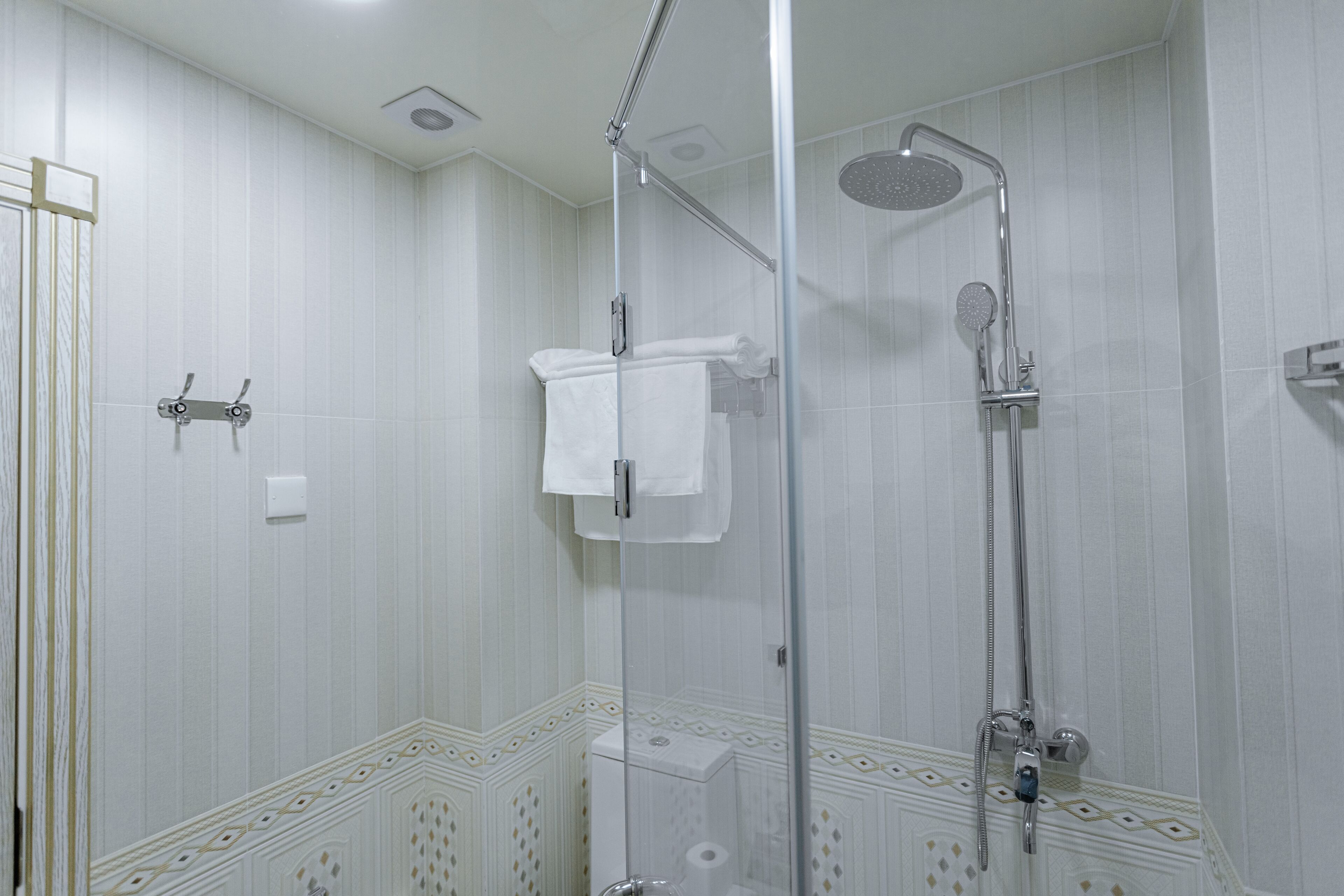 A modern bathroom with a glass-enclosed shower, a toilet, and a towel rack.