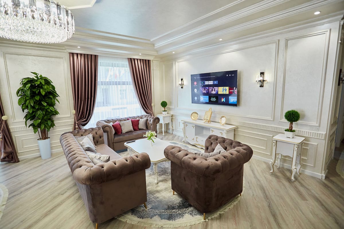 A luxurious living room with a large flat-screen TV, plush brown sofas, and elegant decor.