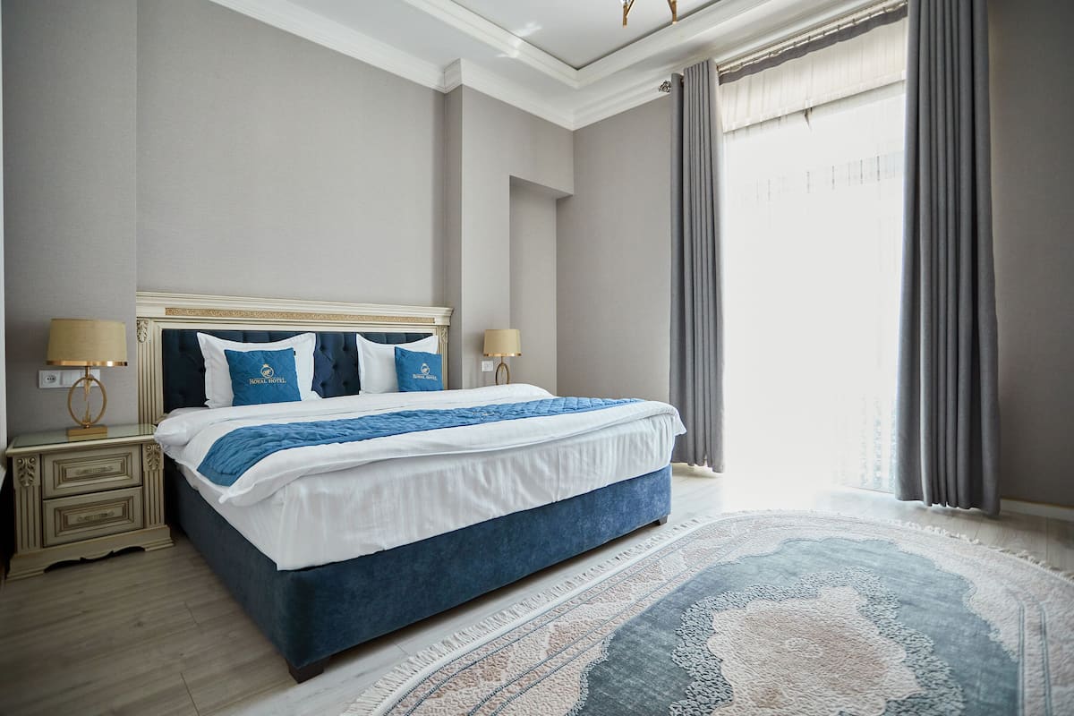 A hotel room with a large bed, two bedside lamps, a nightstand, and a patterned rug.