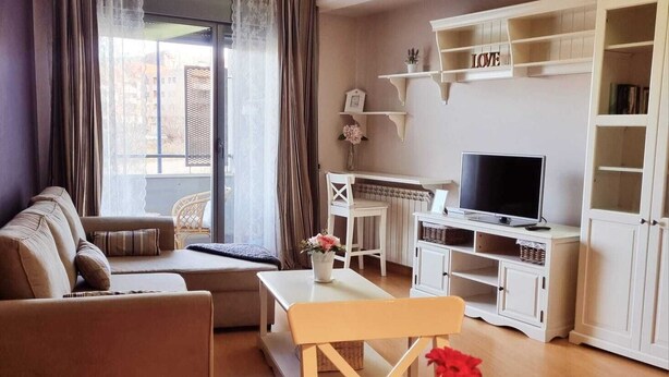 Ein Wohnzimmer mit einer Couch, einem Couchtisch, einem Fernseher und einem Bücherregal.
