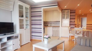 Ein modernes Wohnzimmer mit Flachbildfernseher, einer Couch, einem Couchtisch und einem Essbereich mit Tisch und Stühlen.