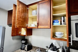 A kitchen with wooden cabinets, a coffee maker, a toaster, and a microwave. - Unique 1 Bedroom House in San Jose (San Jose)