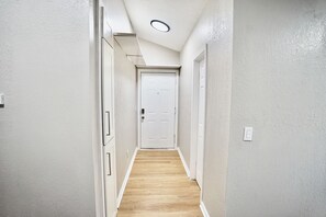 A narrow hallway with a wooden floor, white walls, and a white door at the end. - Unique 1 Bedroom House in San Jose (San Jose)