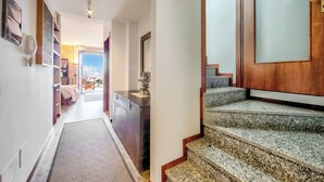 Ein Flur mit Teppichboden, einer Holztreppe und einer Tür zu einem Zimmer mit Blick.