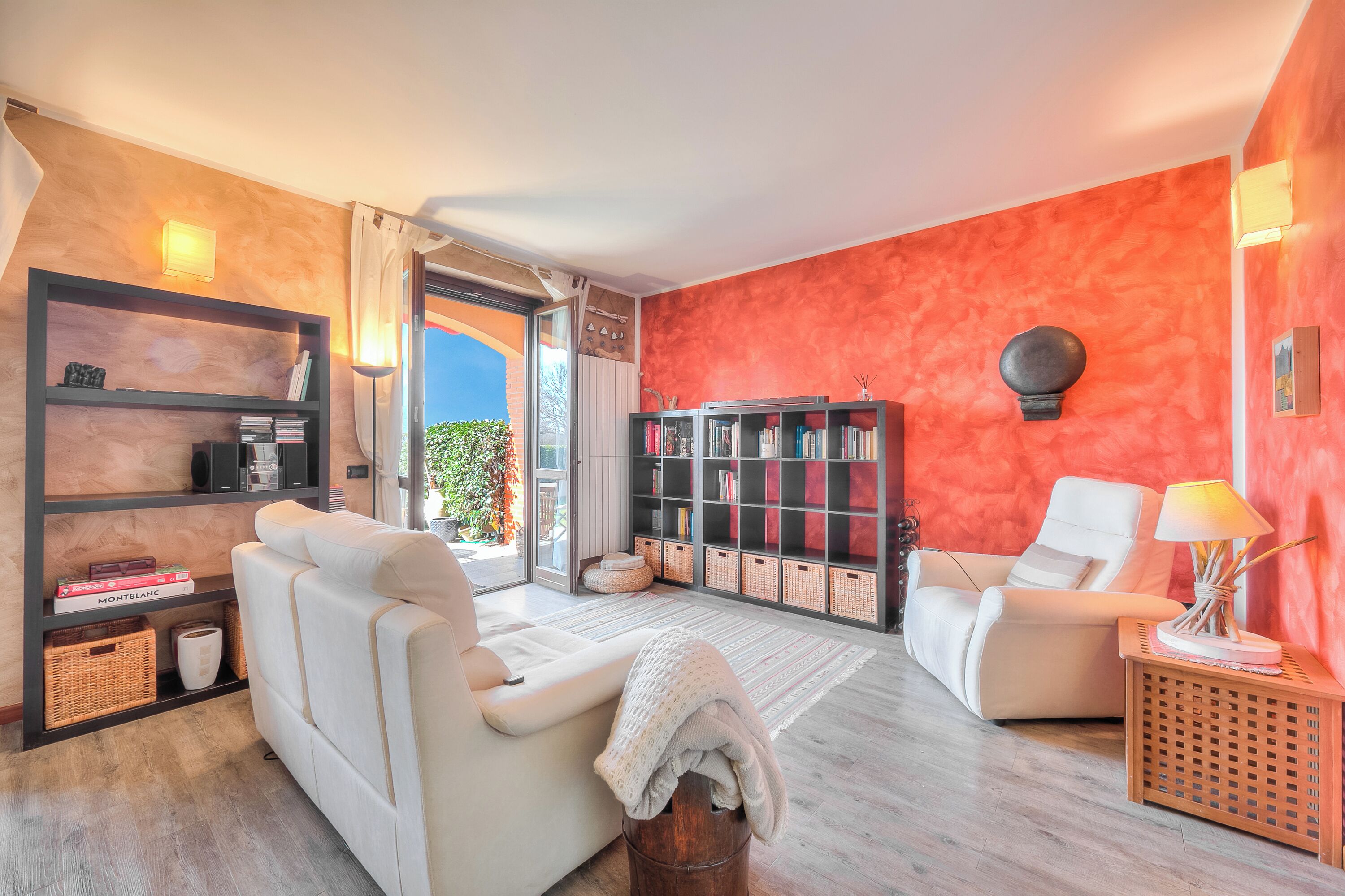 A living room with a sofa, armchairs, a bookshelf, and a lamp.