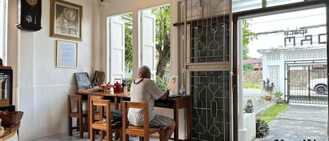 A room with a wooden table, chairs, a clock, and a door leading outside.