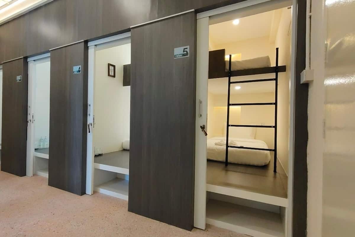 Un pasillo de hotel con varias habitaciones, cada una con una puerta numerada y un cartel que dice 'Relax'.