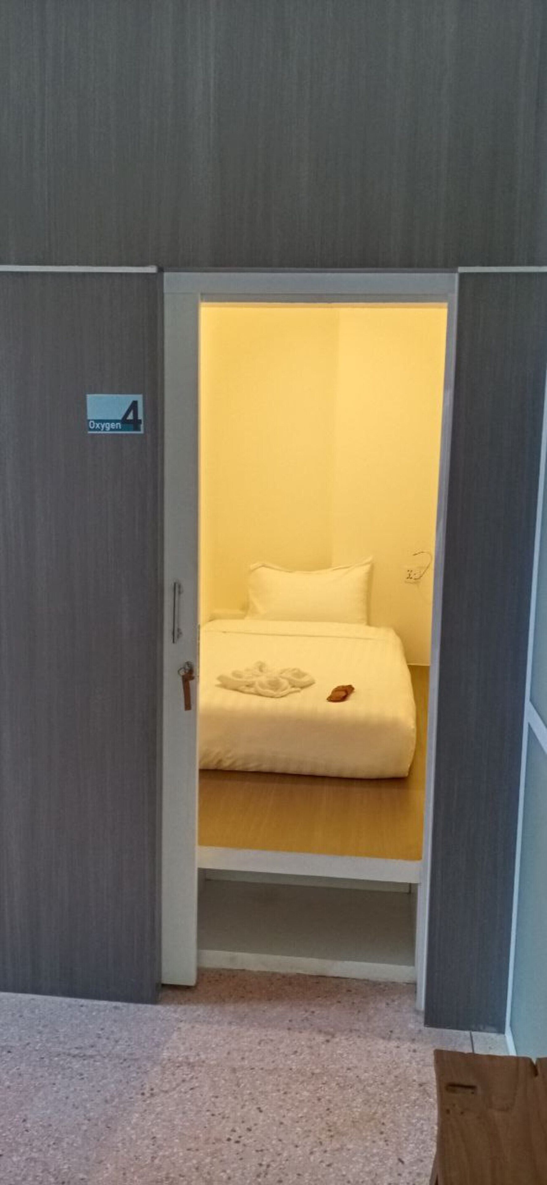 Quarto com cama, armário e placa indicando disponibilidade de oxigênio.
