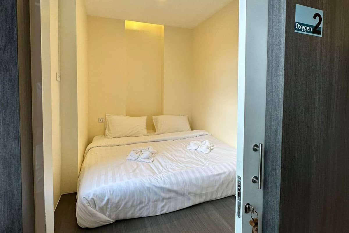Una habitación de hotel con cama, una puerta con el número y un equipo de aire acondicionado.