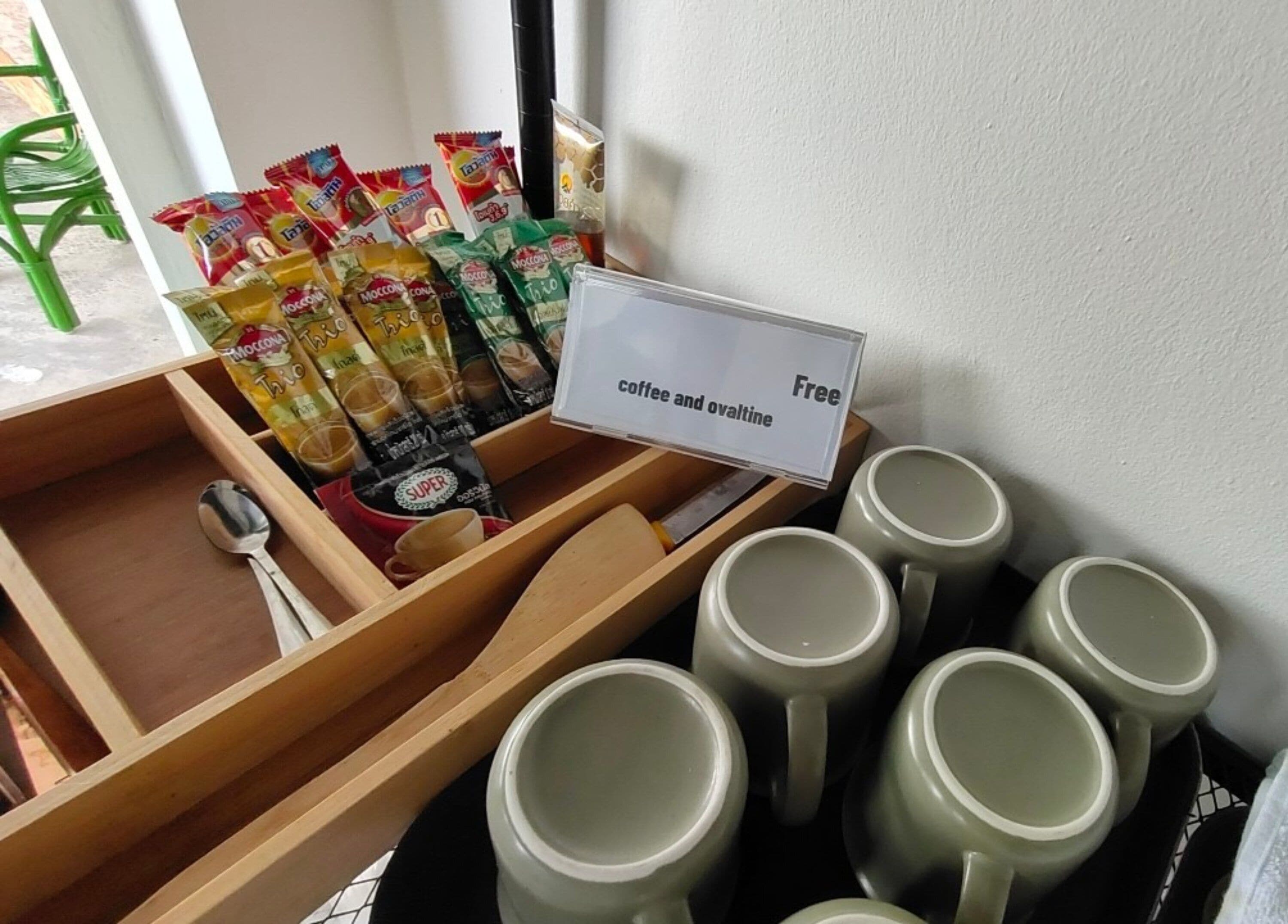 A tray with coffee and snacks, a sign indicating 'coffee and ovaltine free', and several mugs.