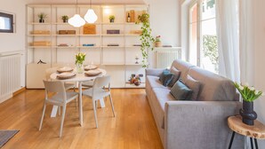 Una sala de estar moderna con comedor, techo de madera, paredes blancas y un ventanal grande.