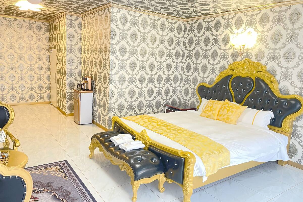A luxurious bedroom with a large bed, a bedside table, and a chair.