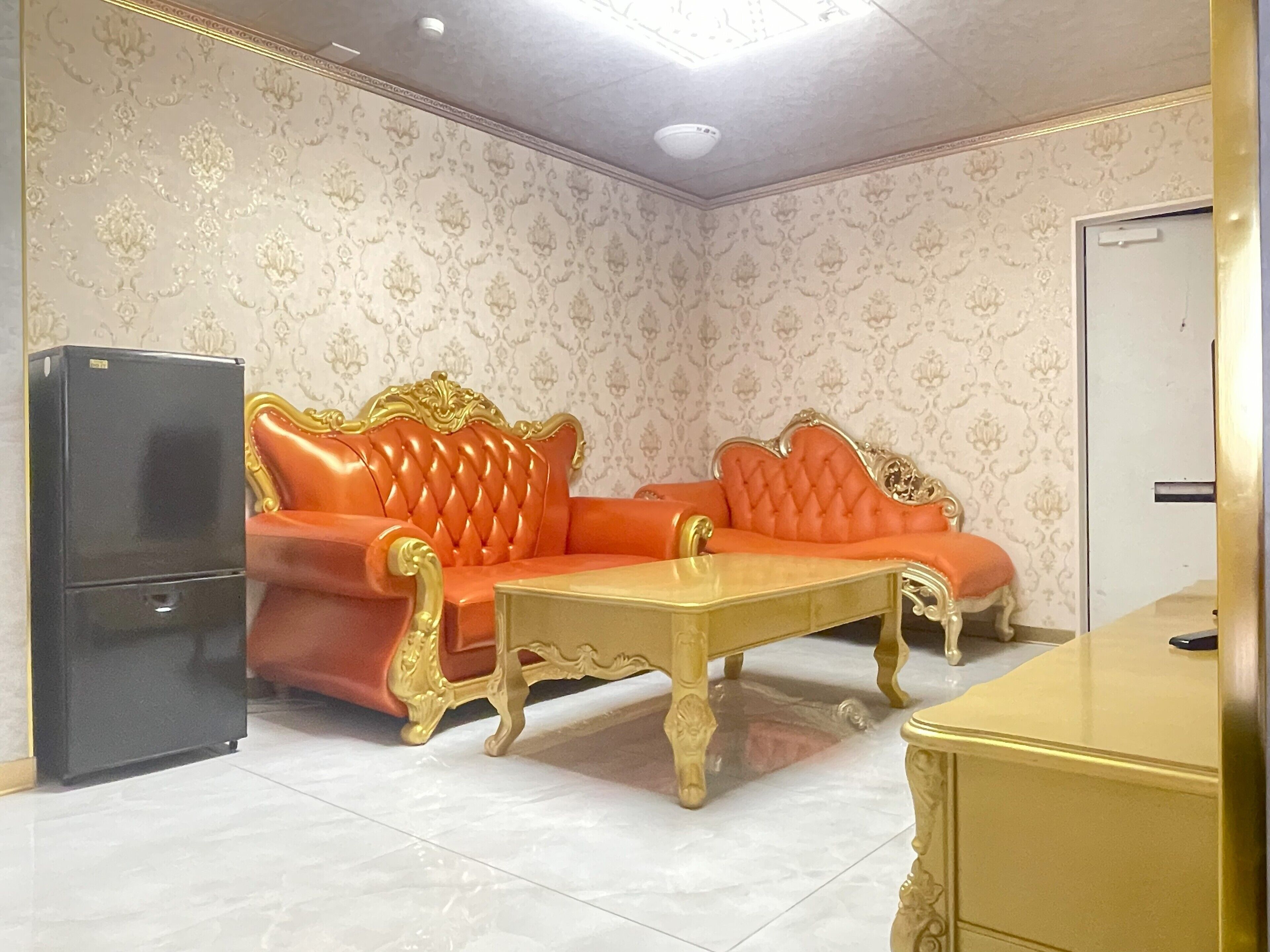 A room with a sofa, a table, and a refrigerator.