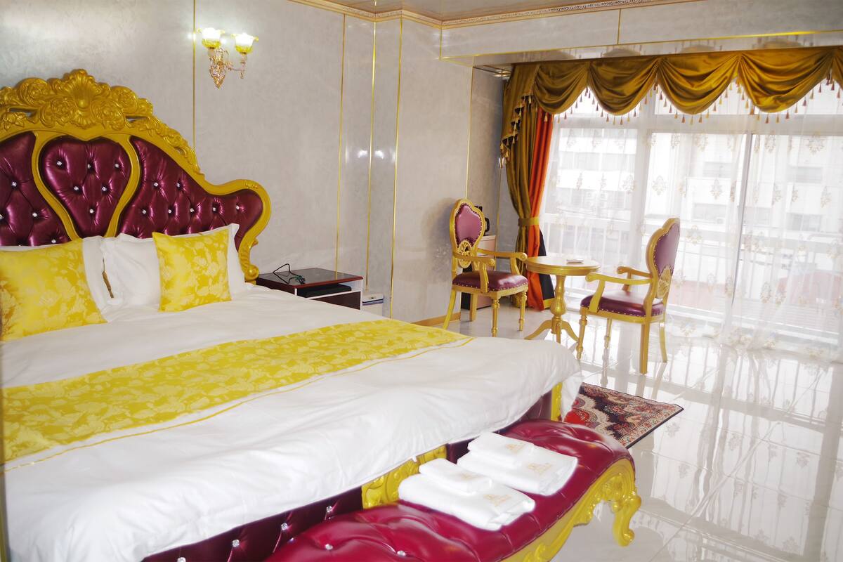 A luxurious hotel room with a large bed, a desk, and a chair.