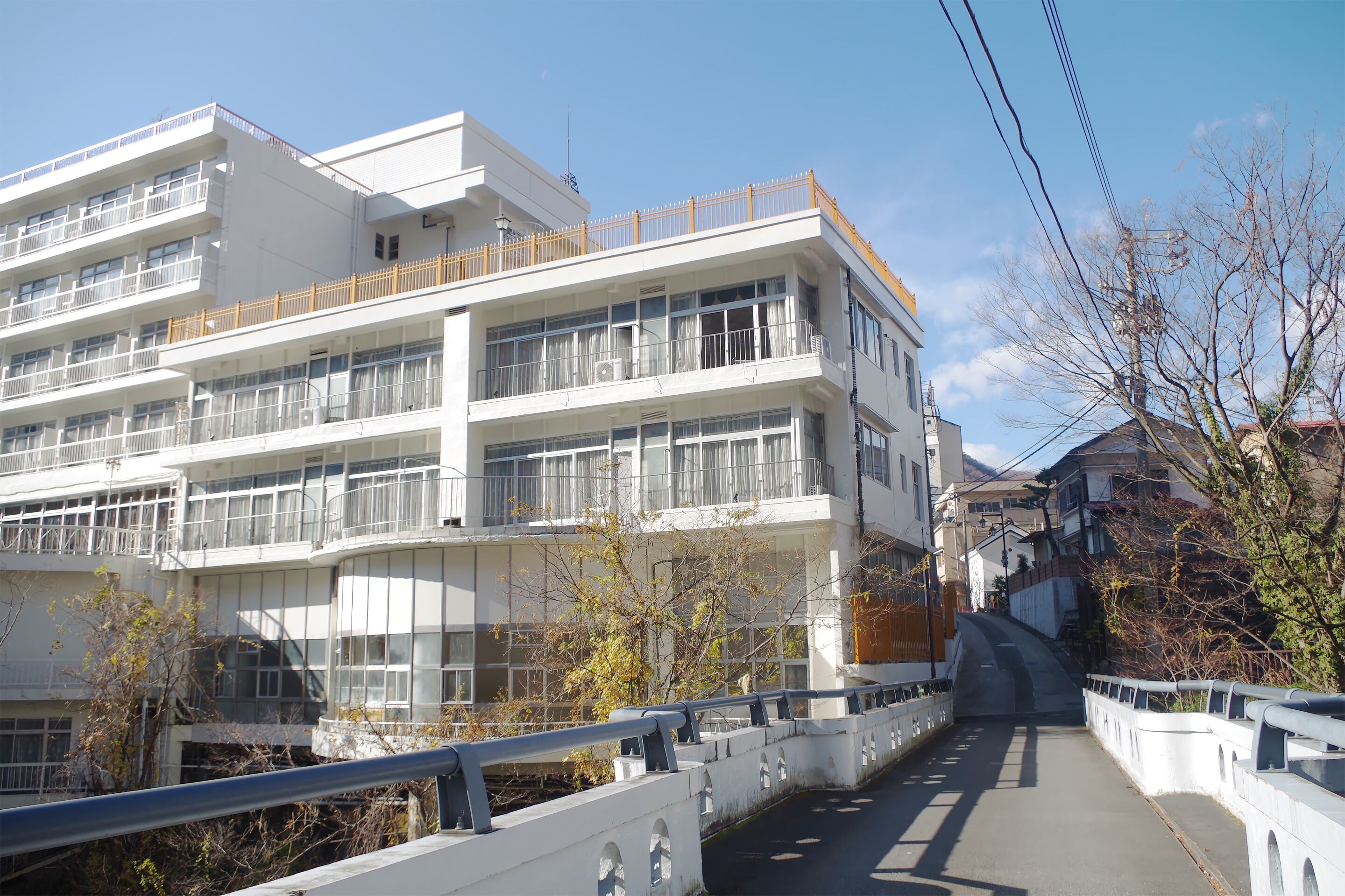 A multi-story building with balconies, a bridge, and a clear sky.