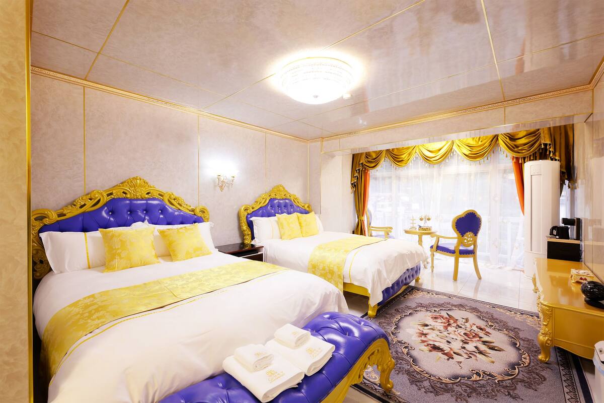 A hotel room with two beds, a sitting area, and a desk.