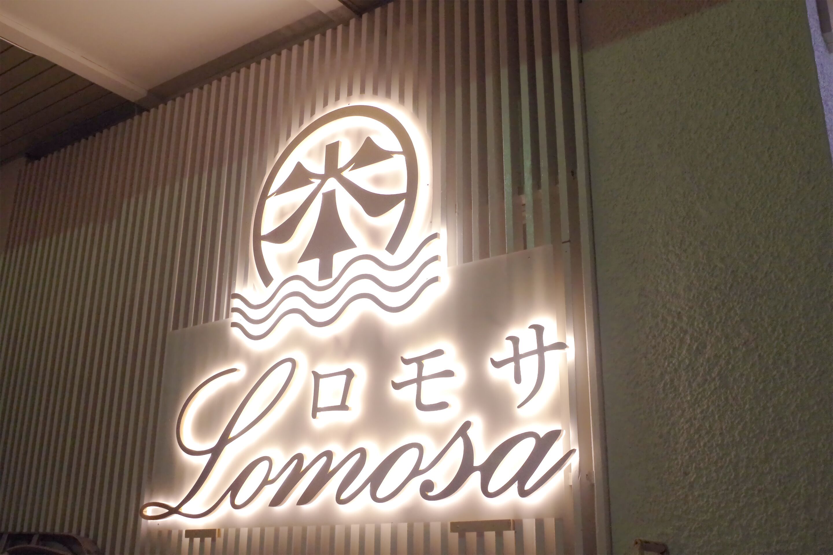 Une enseigne portant le nom « Lomosa » et un logo placé au-dessus.