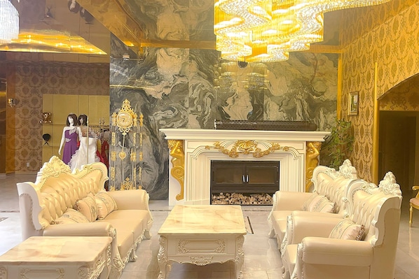 Un salón lujoso con muebles ornamentados, chimenea y una gran lámpara de araña.