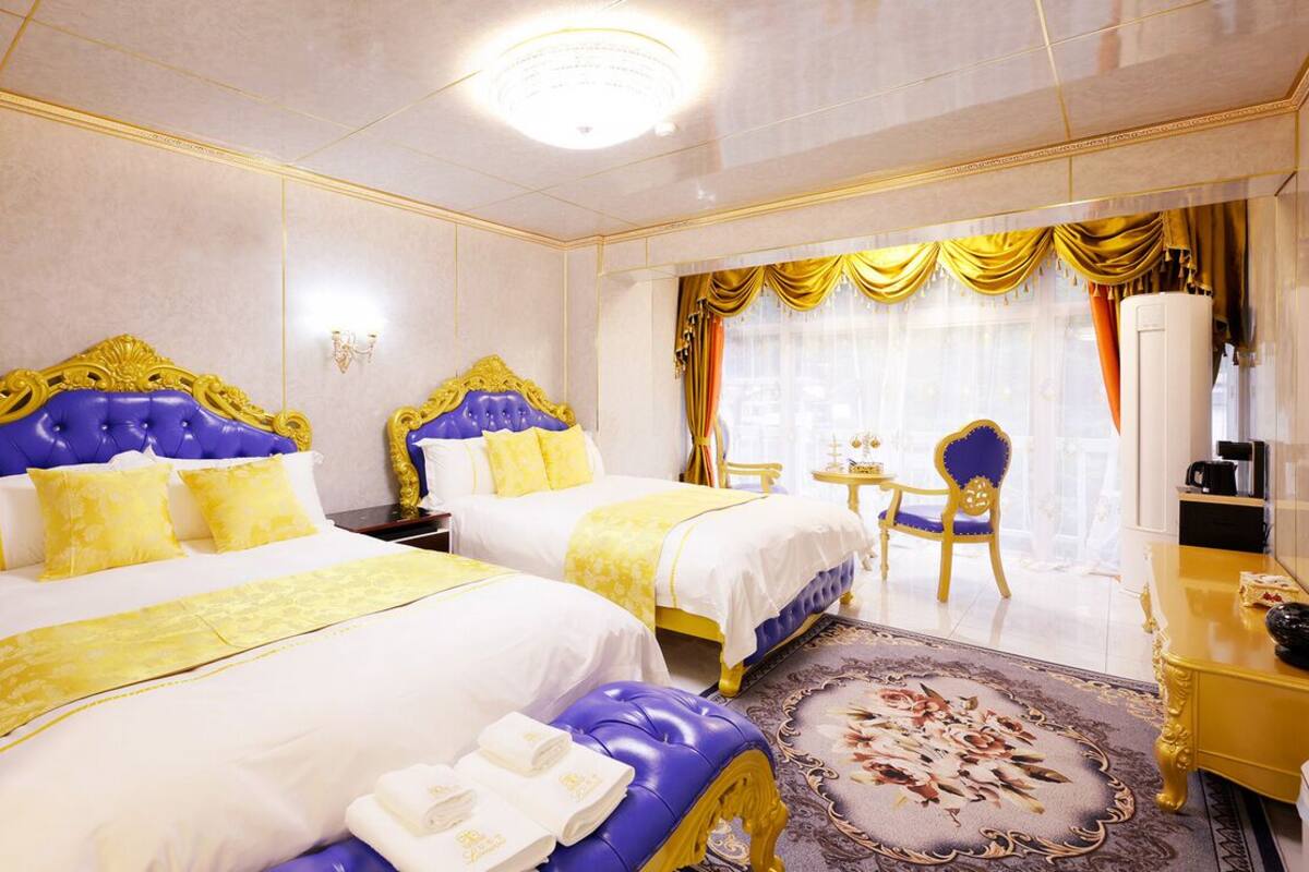 A hotel room with two beds, a sitting area, and a television.