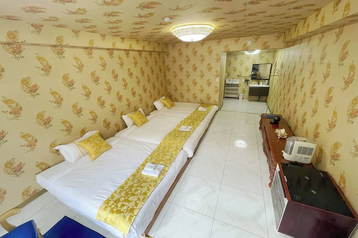 A hotel room with a large bed, a desk with a computer, and a bathroom visible through an open door.