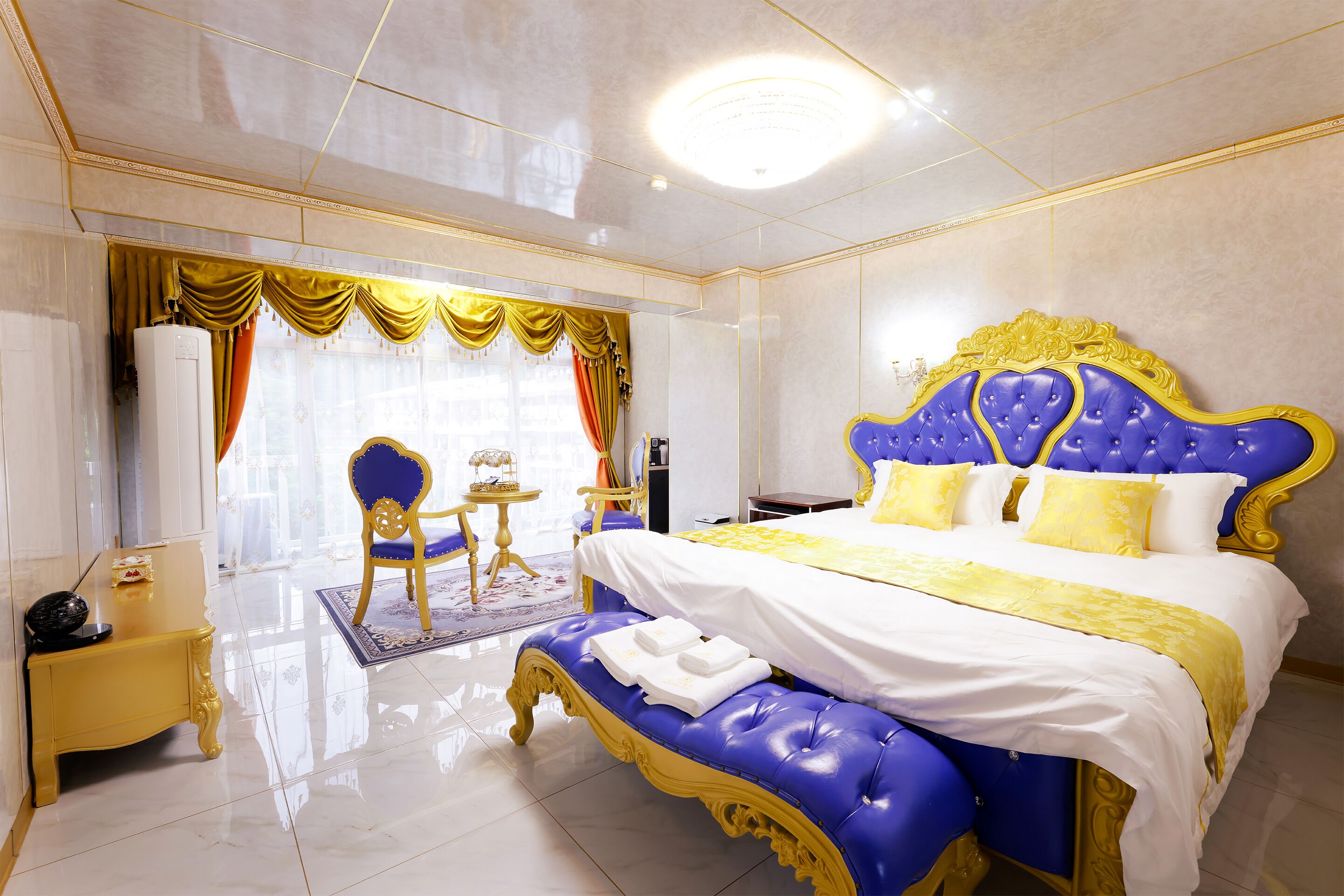 Un dormitorio lujoso con una cama grande, una mesita y una silla.