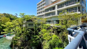 Un hotel de varios pisos con balcones, rodeado de exuberante vegetación y un río.