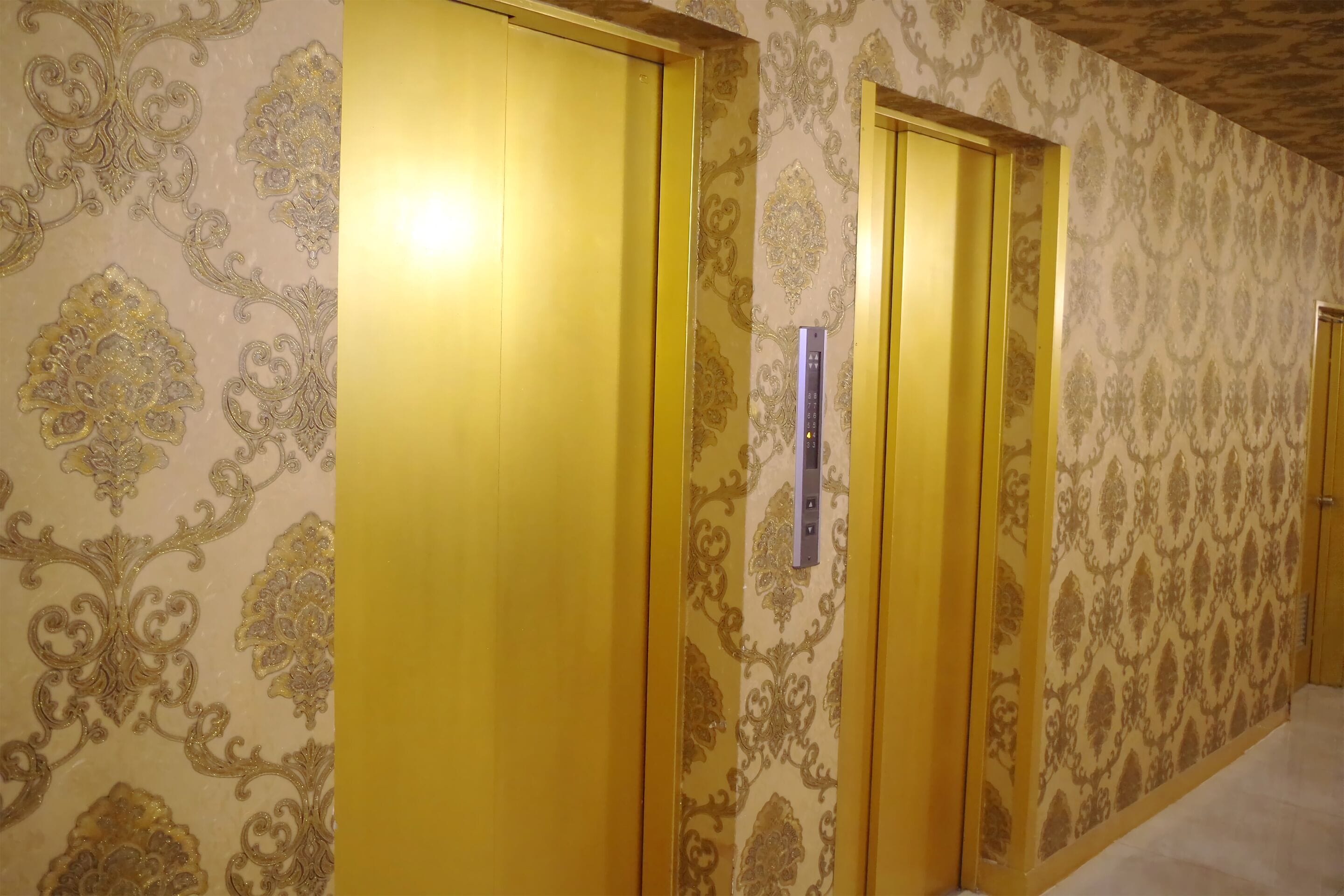 A hallway with patterned wallpaper and wooden doors.