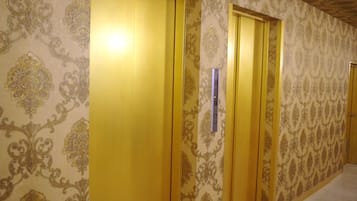 A hallway with patterned wallpaper and wooden doors.