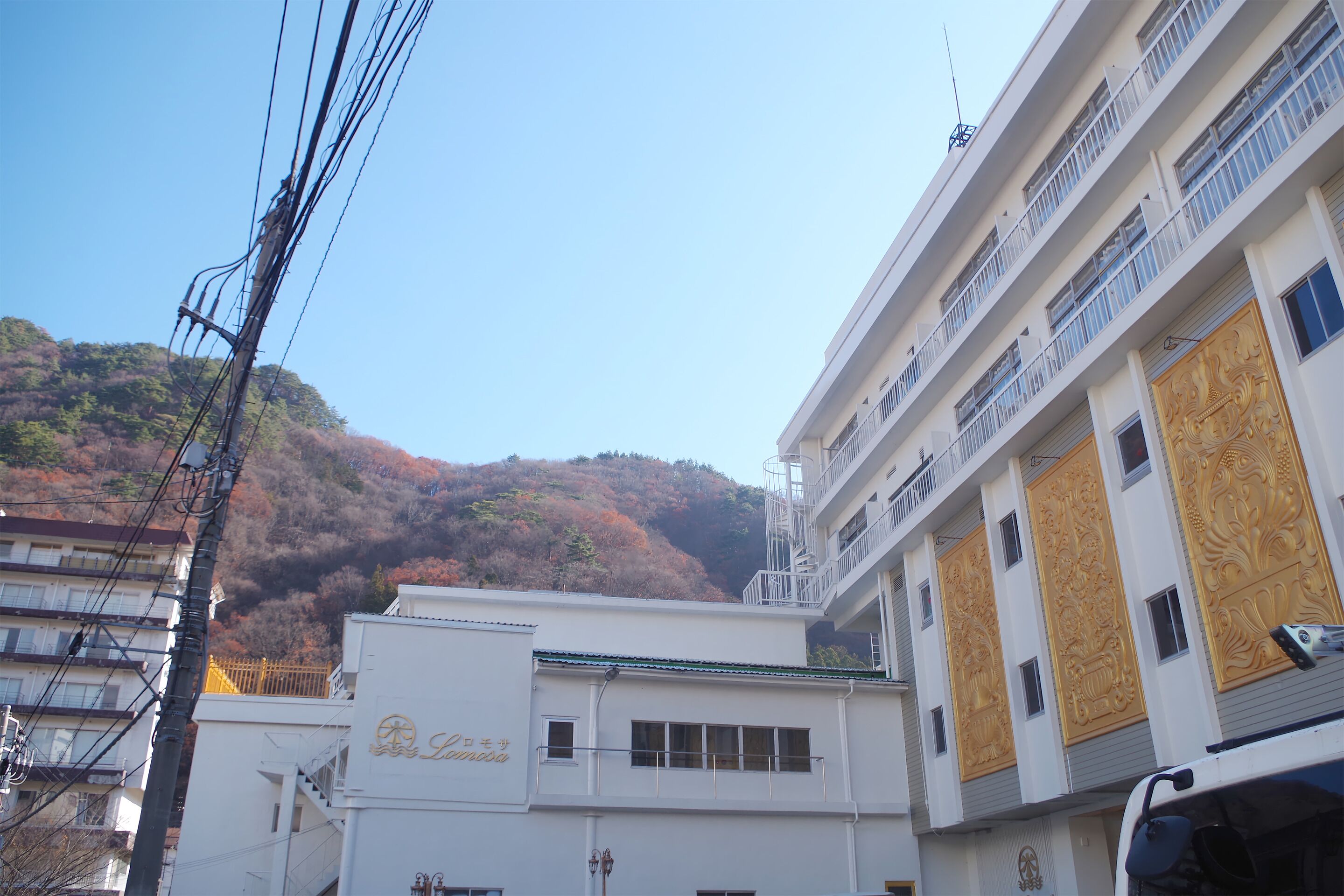 A multi-story building with balconies and a mountain in the background.