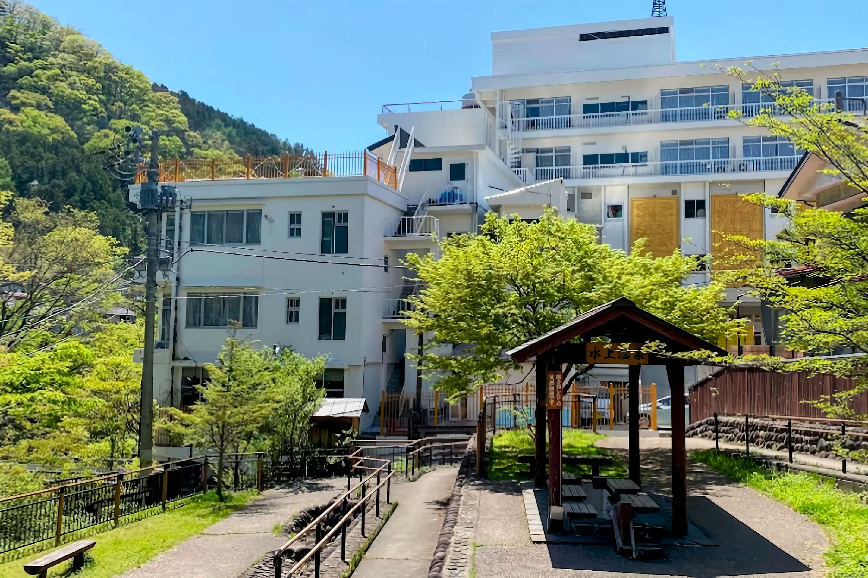 A multi-story building with a covered outdoor seating area and a wooden fence.