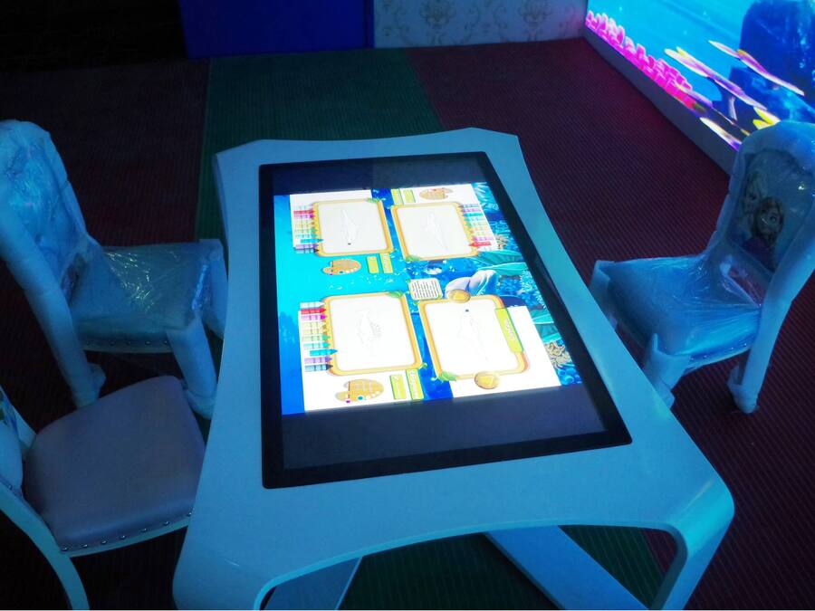 Een tafel met een scherm waarop een spelinterface wordt getoond, omringd door twee stoelen met decoratieve details.