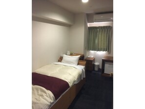 Cozy retreat with a single bed, bedside table, and lamp, perfect for a restful stay.
