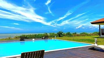 Relax by the ocean with a clear view from our pool area, surrounded by lounge chairs.