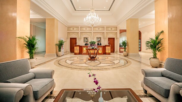 A spacious lobby with a reception desk, two sofas, a chandelier, and potted plants. - Regenta Central Lucknow by Royal Orchid Hotels Limited (Lucknow)