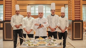 A group of chefs standing in a modern dining area with wooden paneling and large windows. - Regenta Central Lucknow by Royal Orchid Hotels Limited (Lucknow)