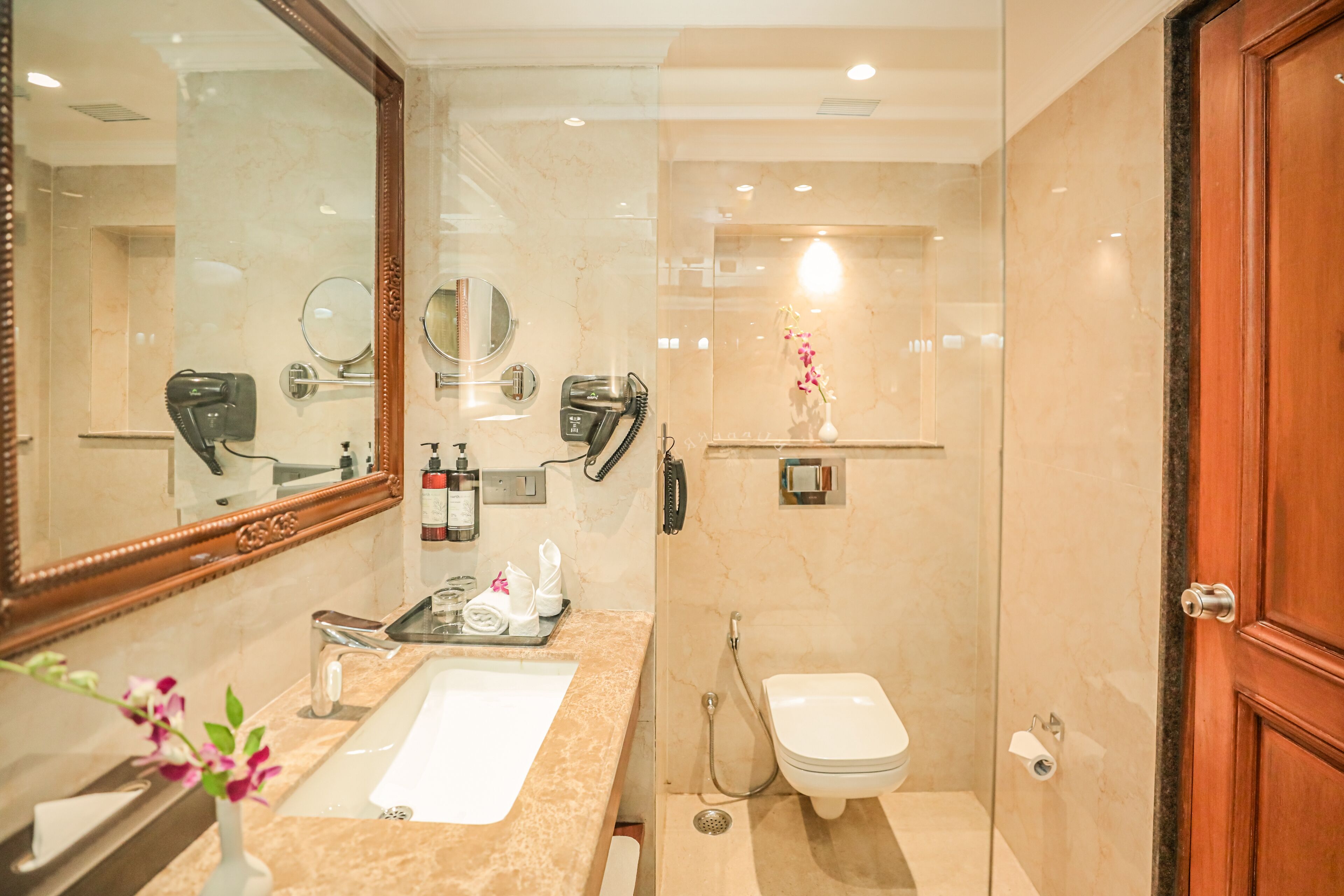 Un baño moderno con un espejo grande, un lavabo, un inodoro y una ducha.
