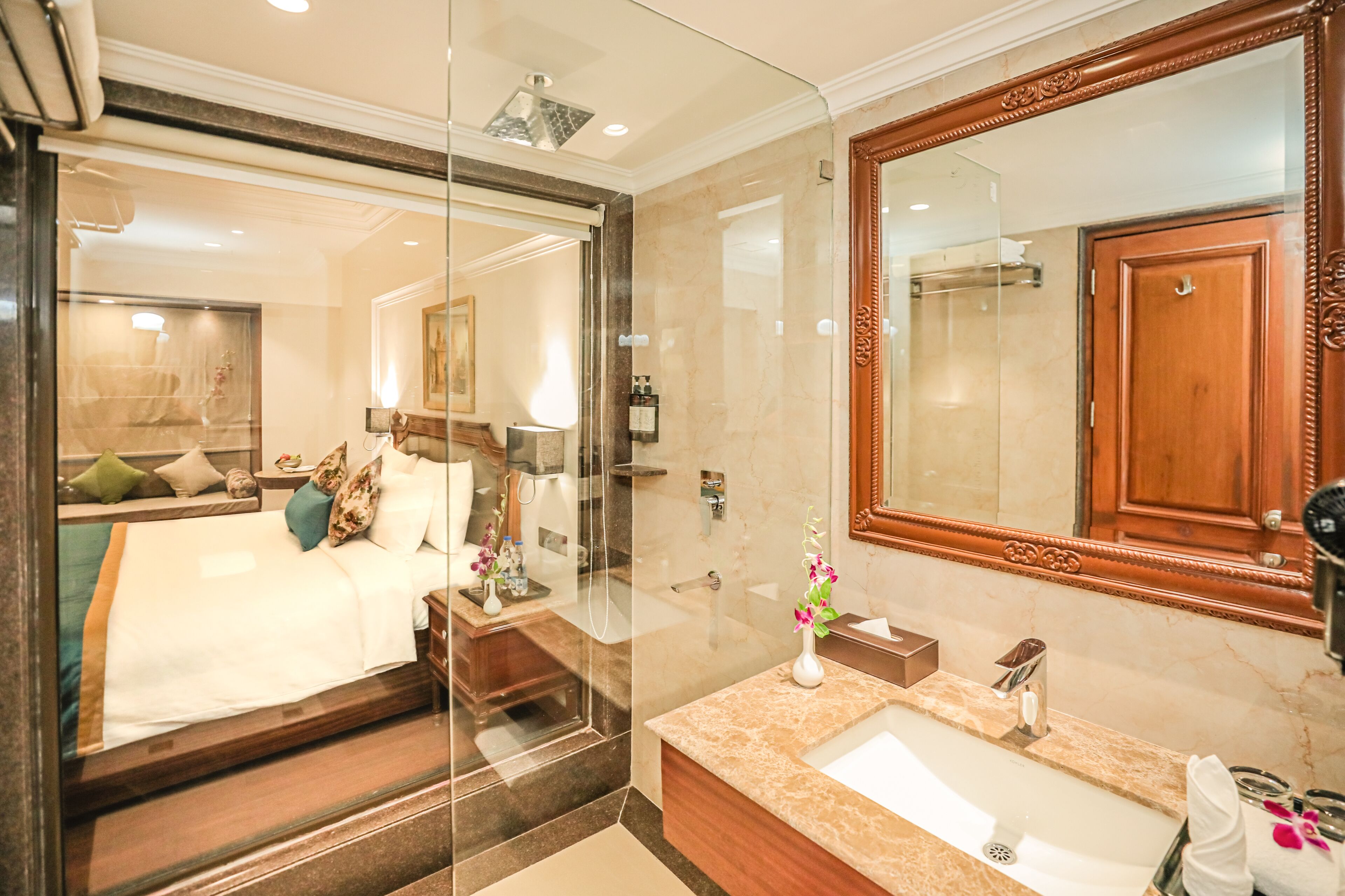 A hotel room with a large bed, a bathroom with a marble sink, and a large mirror.
